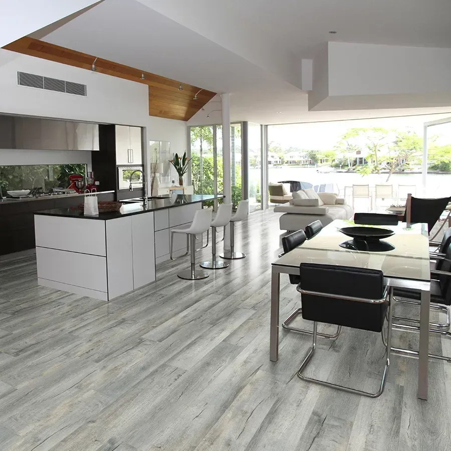 Modern kitchen and dining area with light wood-look flooring, white cabinets, and waterfront views.