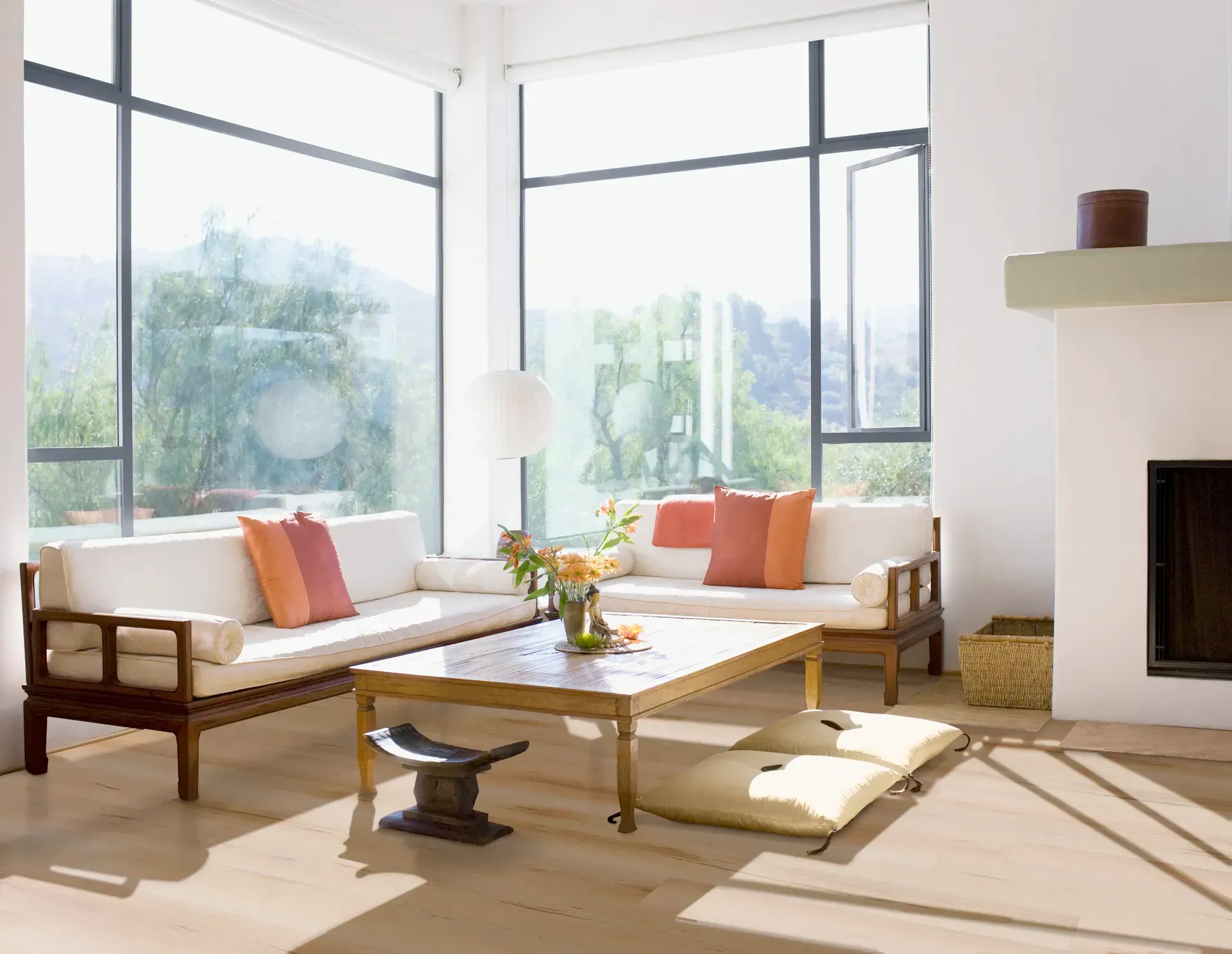 A modern living room with sunlight, two beige sofas, wooden coffee table, and floor-to-ceiling windows.