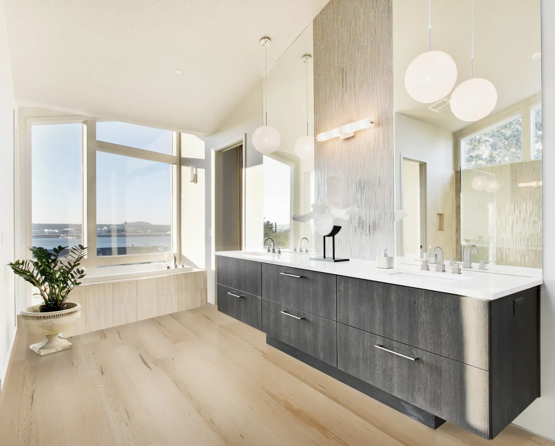 Modern bathroom with wooden floor, a double vanity, large mirror, and large window with a view.