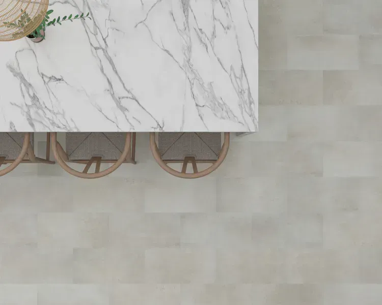 Overhead view of a marble-topped table with two wicker chairs, set on a neutral-toned tile floor.
