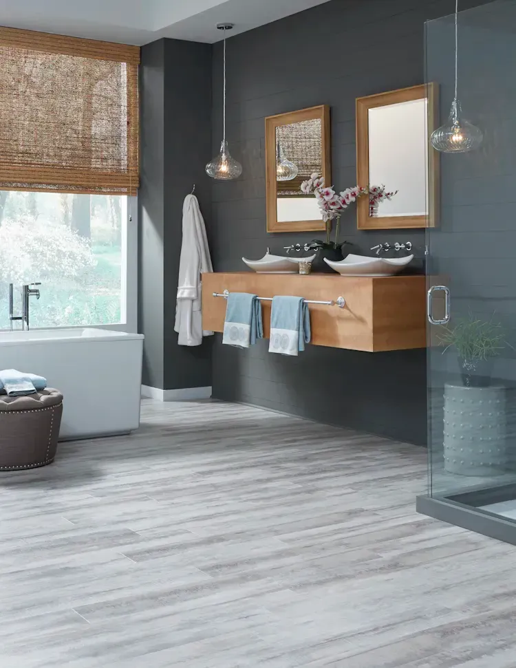Modern bathroom with gray walls, wood vanity, vessel sinks, and light wood-look floor.