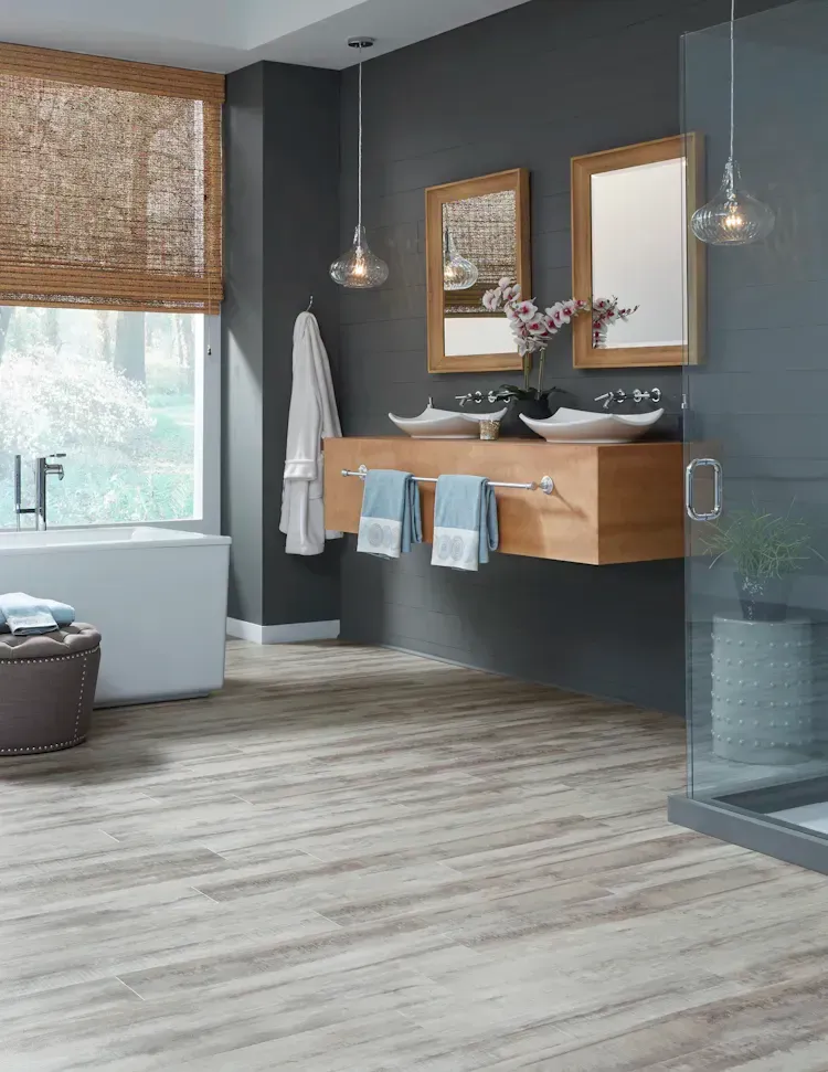Modern bathroom with wood floors, gray walls, floating vanity, and glass shower.
