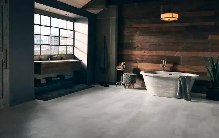 Bathroom with concrete floor, wood accent wall, and freestanding tub by window.