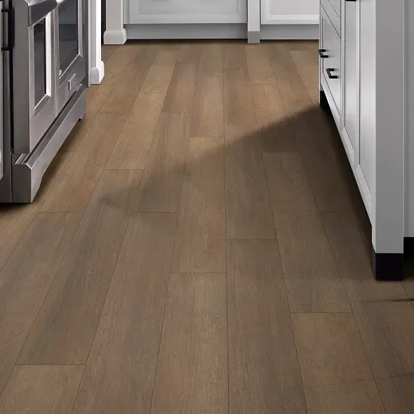 Wooden kitchen floor with a medium brown tone, between cabinets and oven.