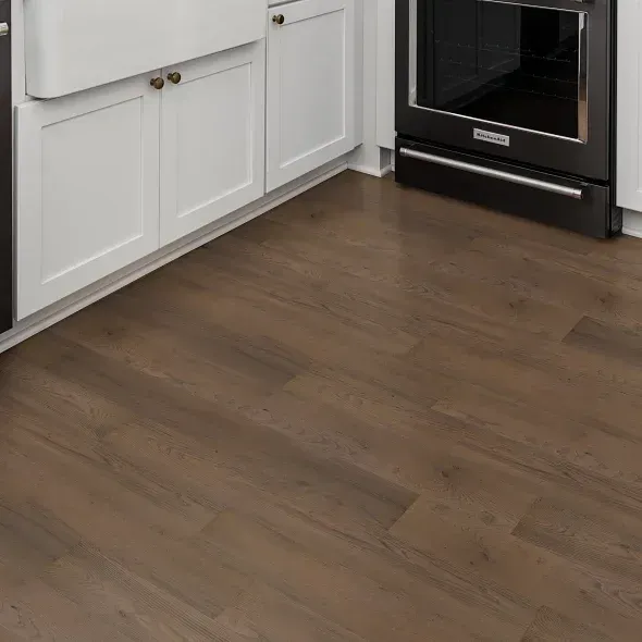 Dark wood-look flooring in a kitchen with white cabinets and black oven.