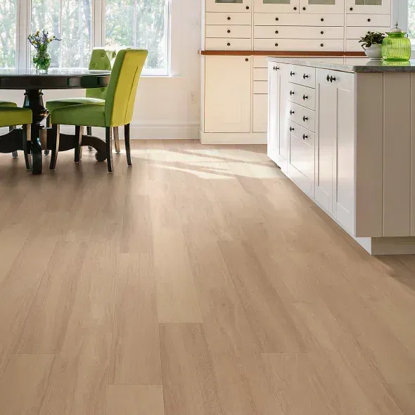 Light wood-look flooring in a bright kitchen with white cabinets, a dark table, and green chairs.
