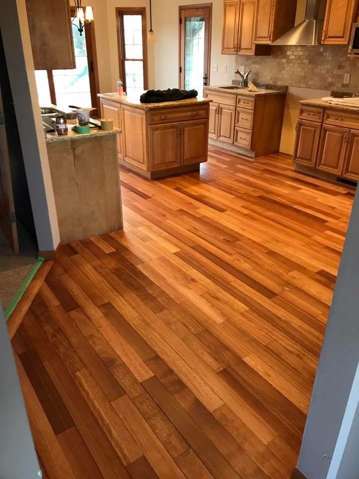 An empty room with hardwood floors and two windows