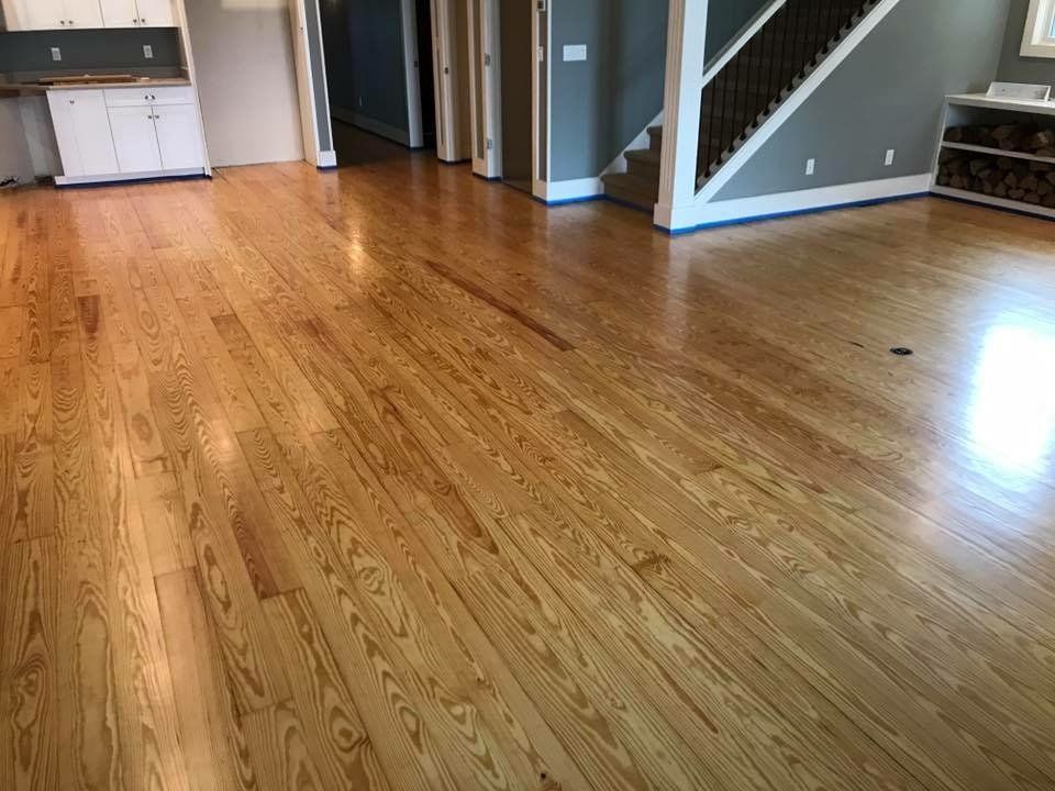 Hardwood floors in a room with white cabinets, a staircase, and gray walls.