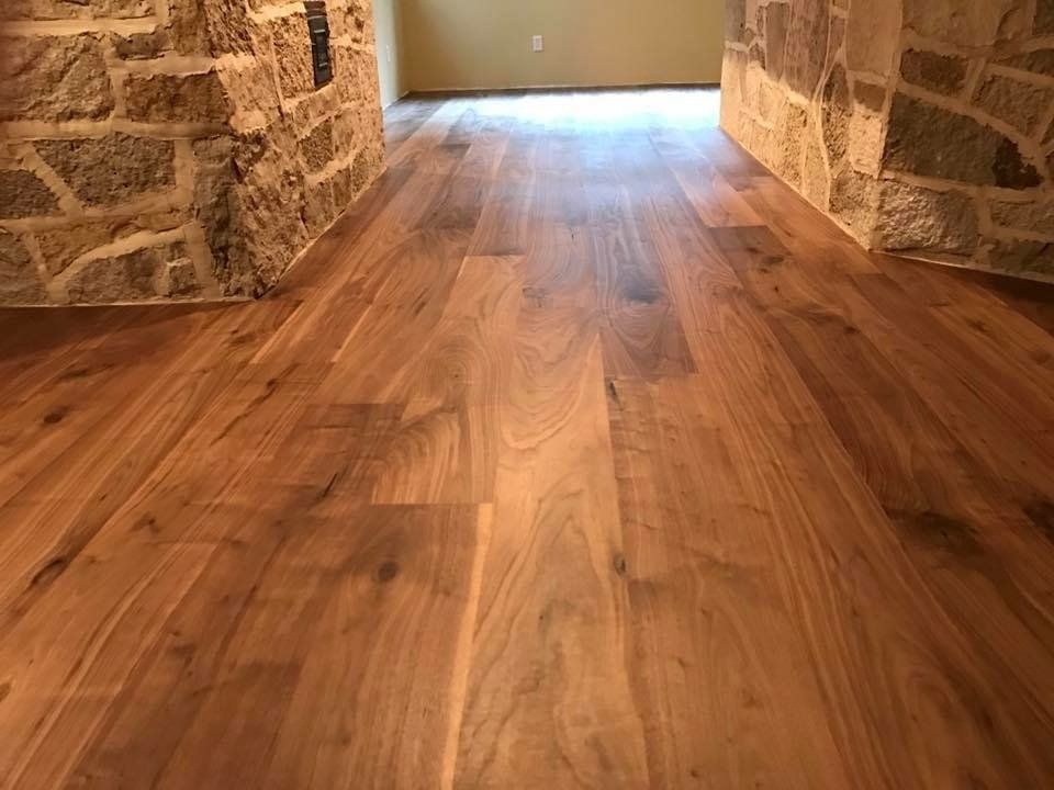 Wooden floor with dark brown planks between stone walls.