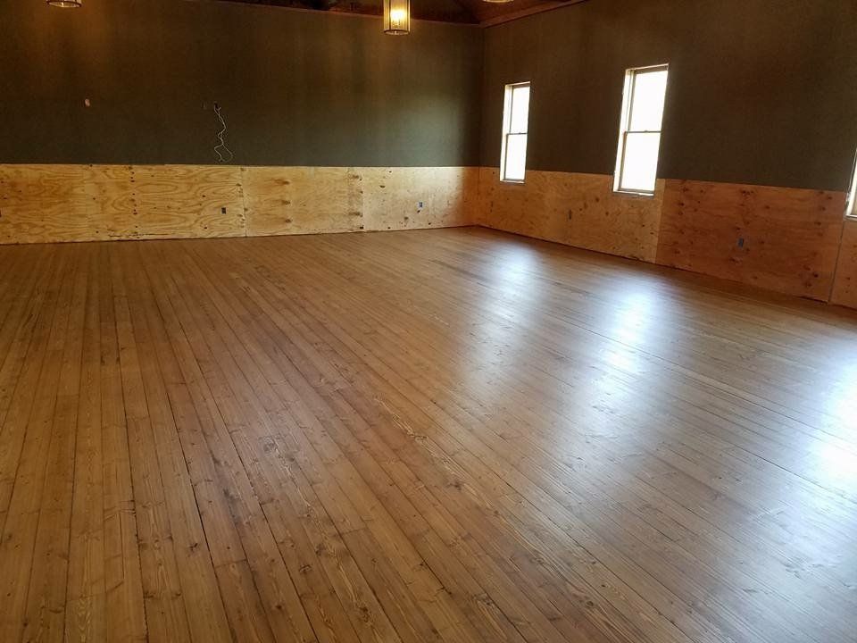 Wooden dance floor in a large room with light wood paneling and dark green walls.
