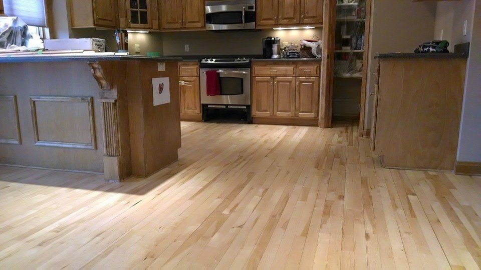 Light wood floor in a kitchen with wooden cabinets, stainless steel appliances, and a breakfast bar.