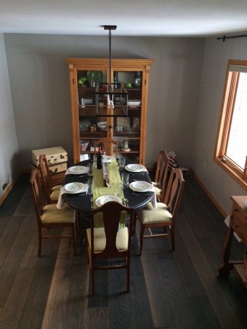 Dining room with a table set for a meal, antique cabinet in the background, hardwood floor.