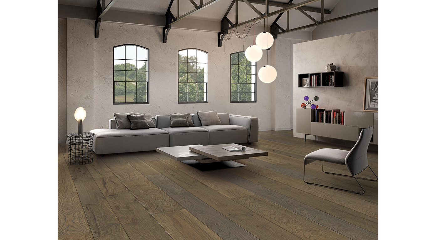 Living room with gray sofa, wooden floor, three windows, and modern decor.