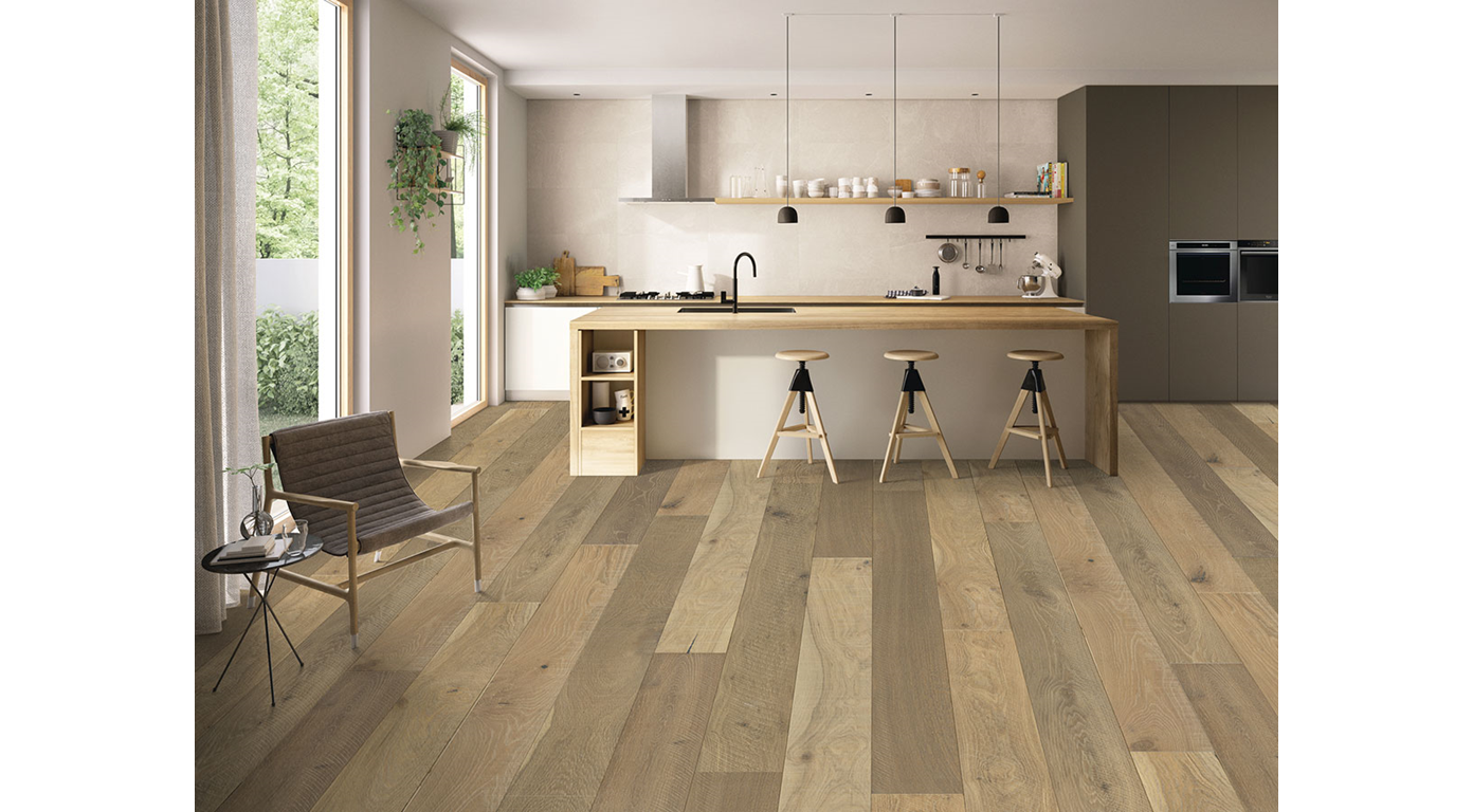 Light wood floor in a modern kitchen with island, bar stools, and a seating area by a window.