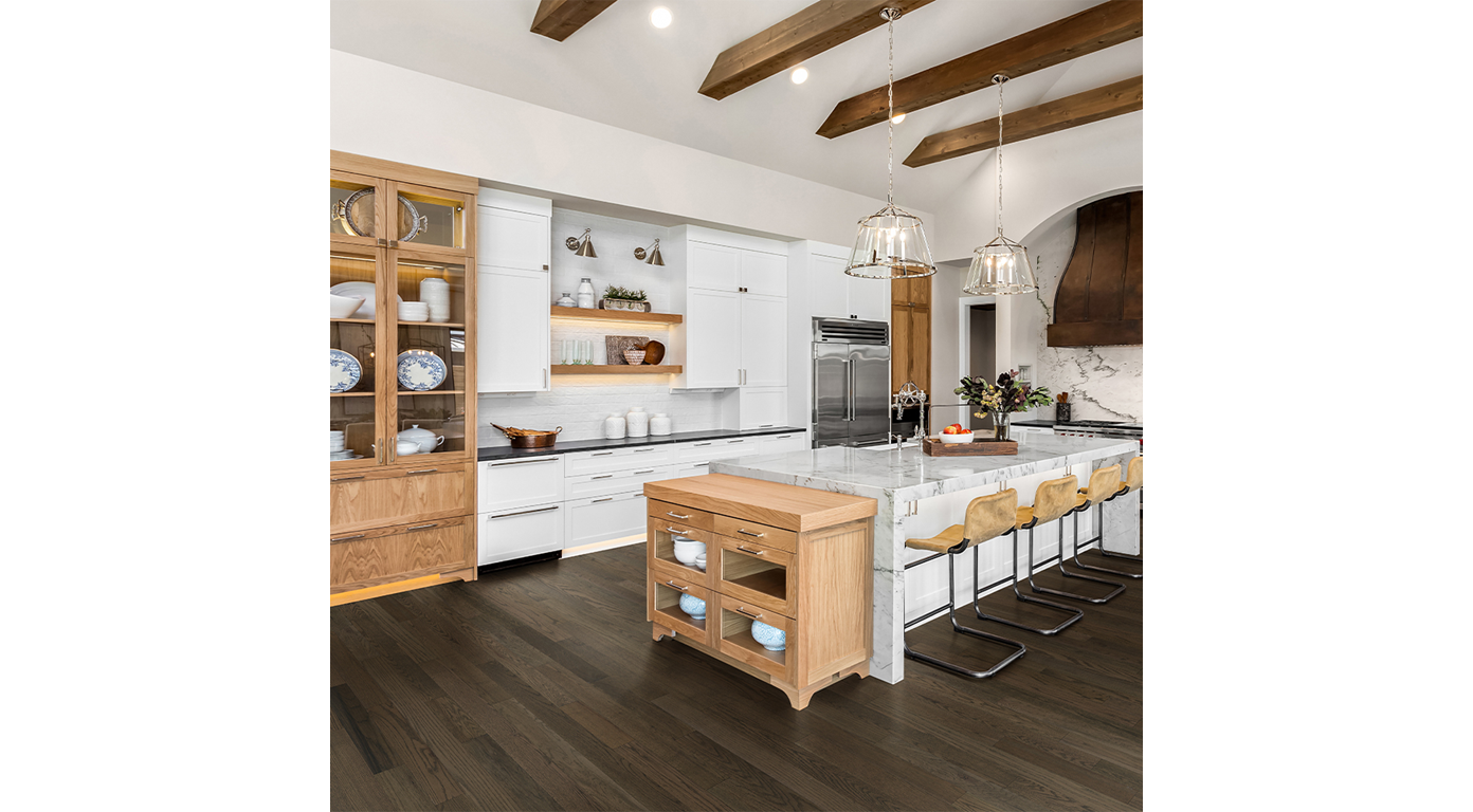 A well-lit kitchen with light wood cabinets, white countertops, and a central island with seating.