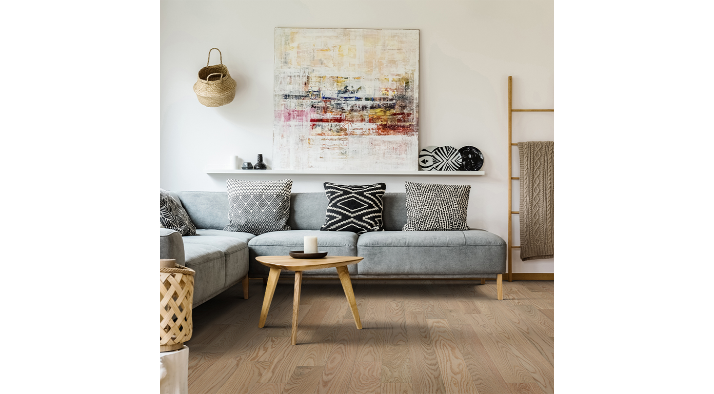 Living room with a gray sectional, wooden coffee table, and abstract art on a white wall.