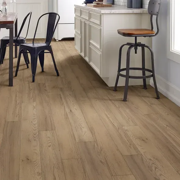 Wooden flooring in a kitchen with a white island, metal chairs and a stool.