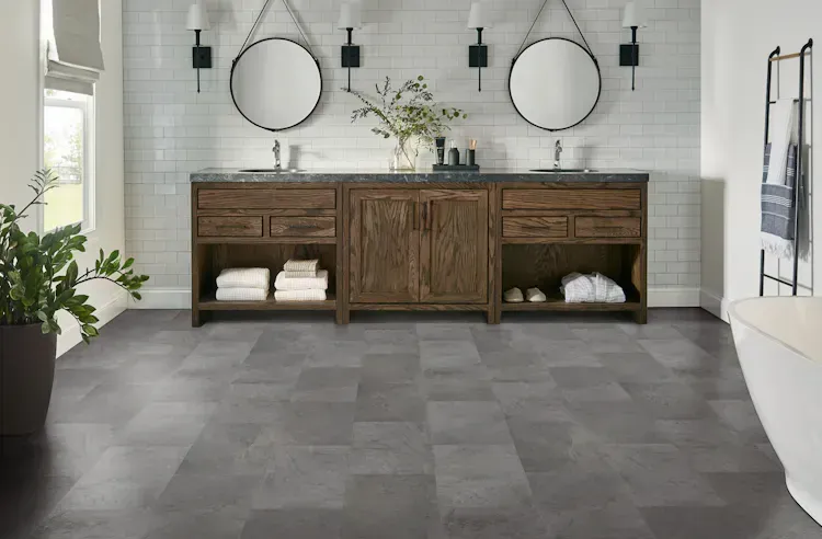 Bathroom with dark gray tile floor, wooden vanity, two mirrors, white tile wall, and a soaking tub.