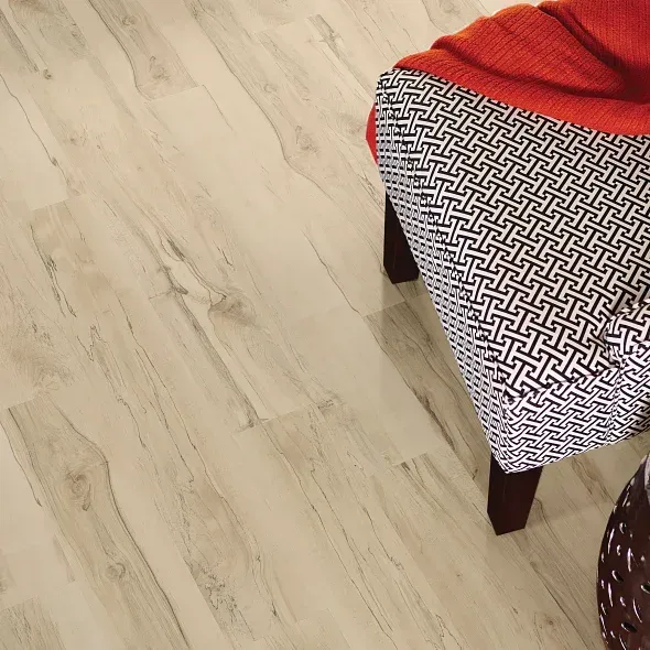 Light wood-look flooring with a patterned stool and a burnt orange blanket.