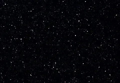 Black surface speckled with white flecks, resembling a starry night sky.