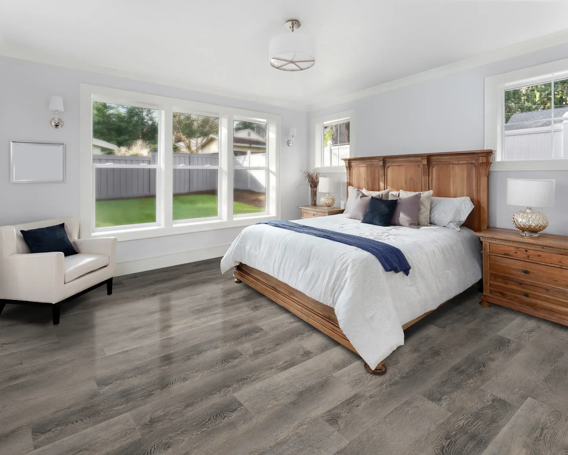 Bedroom with wooden furniture, large windows, and gray wood-look flooring.