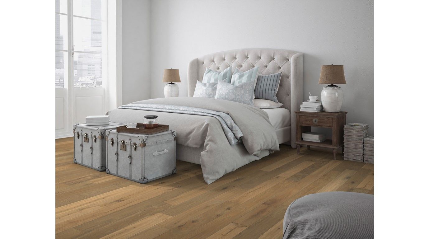 Bedroom with hardwood floor, tufted headboard, white bedding, and a decorative storage trunk.