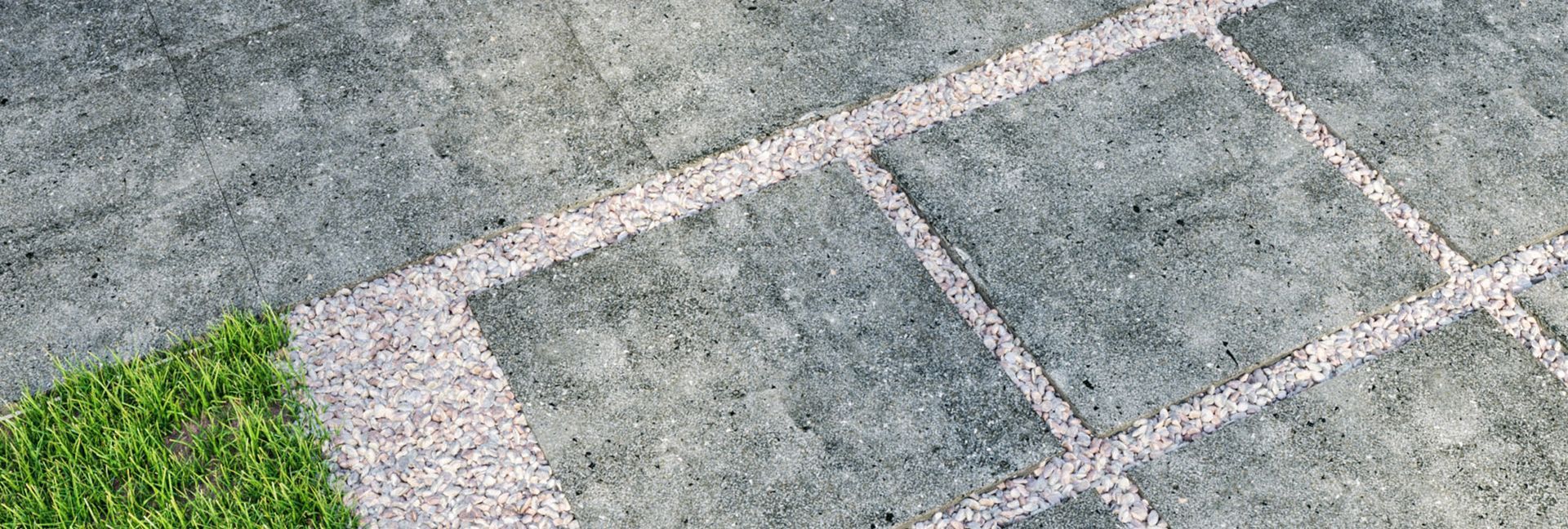 Close-up of a concrete surface with white lines and a patch of green grass.