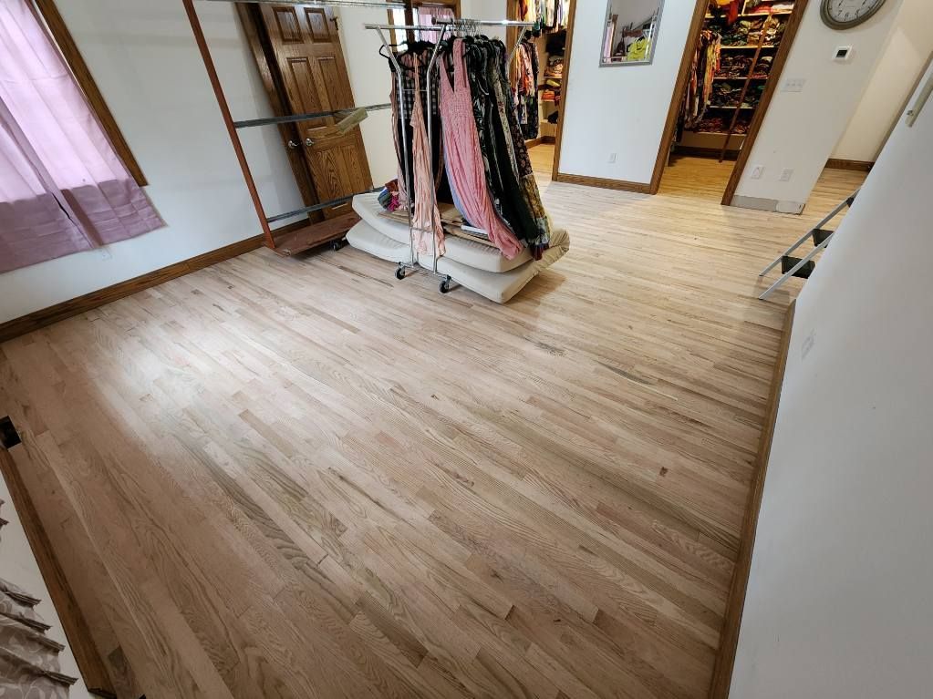 Hardwood floor in a room with clothing rack on a raised platform, doorway, and closet in background.