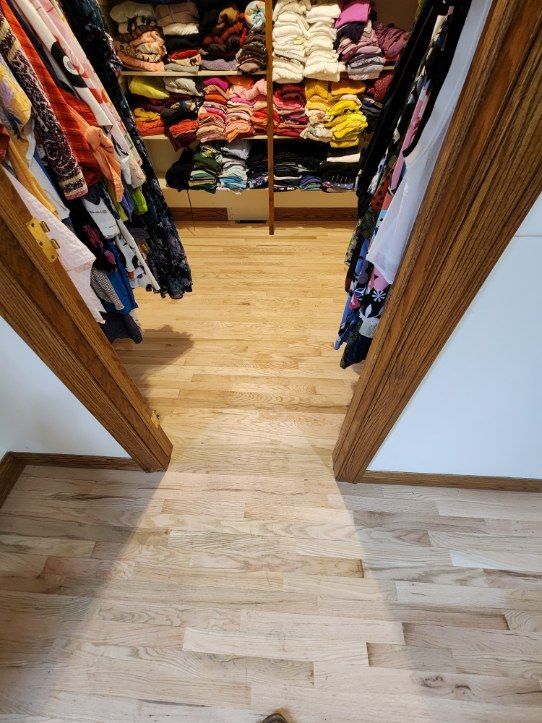 Closet with hardwood floor. Clothes are organized on shelves and hanging on rods.
