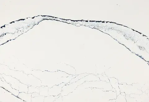 White countertop with dark blue veining and a curved design across the top.