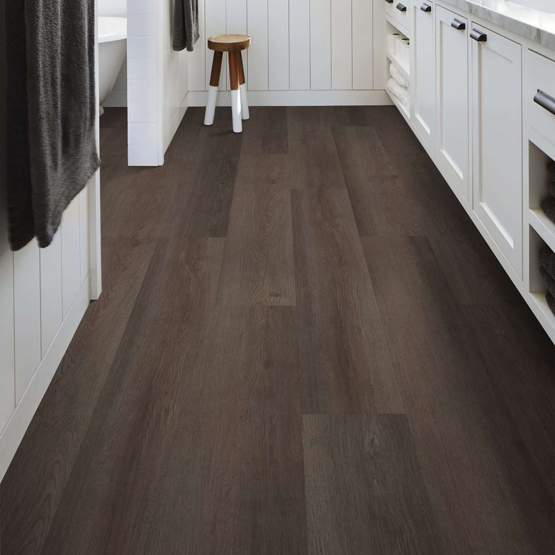 Bathroom with dark wood-look flooring, white cabinets, and a small wooden stool.