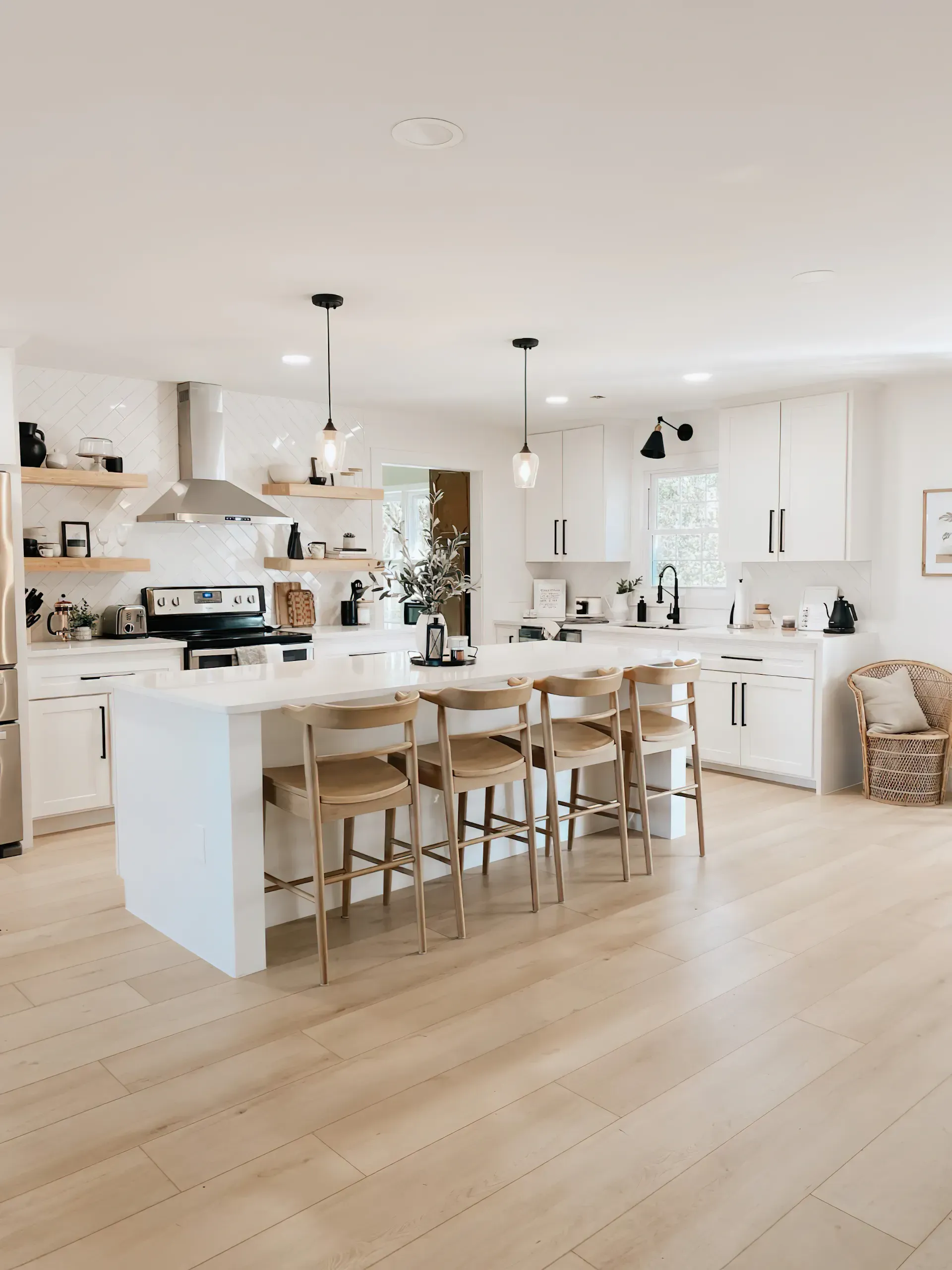 Bright, modern kitchen with white cabinets, island with stools, and light wood floors.