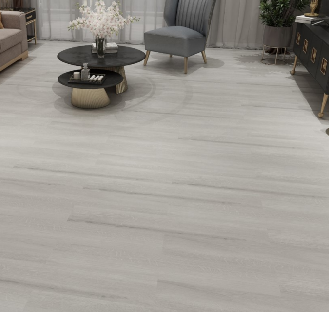 Light-colored hardwood floor in a living room with a gray armchair, table, and couch.