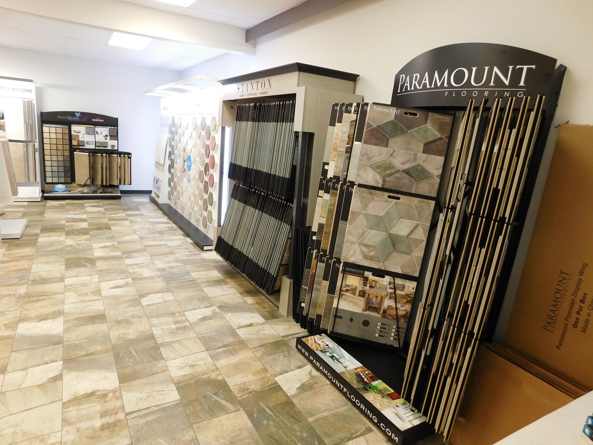 Interior of a tile showroom with various tile samples on display; neutral floors and walls.