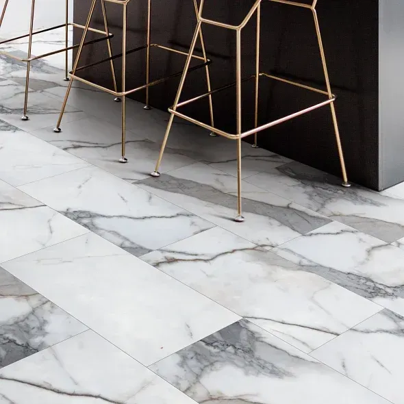 White marble tile flooring with gray veining; gold bar stools.