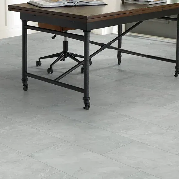 Desk with black metal frame and rolling wheels on gray flooring.