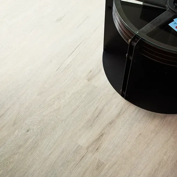Light-colored wooden floor with a black, round table leg in the corner.