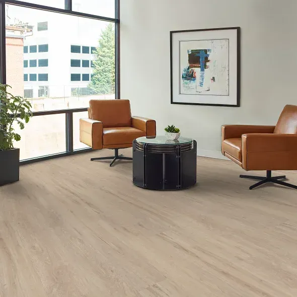 Room with light wood-look flooring, two brown leather chairs, a small black table, and a large window.