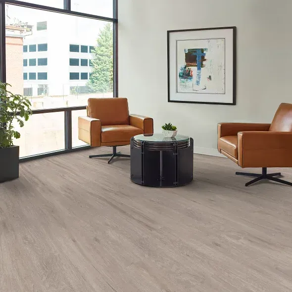 An inviting living room with tan leather chairs, a dark coffee table, and a large window.
