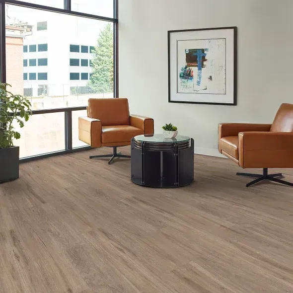 Two brown leather armchairs in a modern living room with wood floors, a window, and a small table.