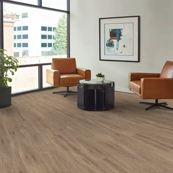 A modern living room with tan flooring, two brown leather chairs, and a black table; a large window.
