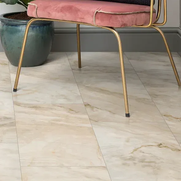 Golden marble-look flooring beneath a pink velvet chair with gold legs and a teal potted plant.