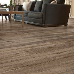 Wooden floor in a living room with a dark gray couch and table in the background.