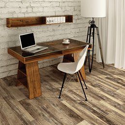 Wooden desk with laptop, white chair, and floor lamp against a brick wall and wood floor.