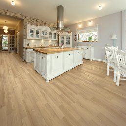 Spacious kitchen with light wood floors, white cabinets, and a central island. Natural light.