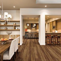 Open-concept dining and kitchen area with wood floors, dining table, and kitchen bar.