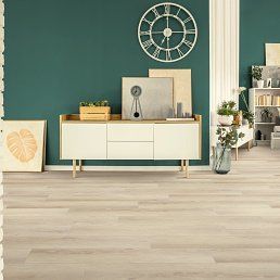 Living room with white cabinet, wooden floor, and green wall with clock and art.