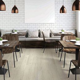 Restaurant interior with wooden tables and chairs, white brick wall, and pendant lights.