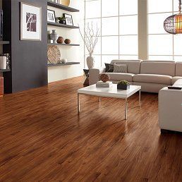 A living room with dark hardwood floors, a light beige sofa, and white modern furniture.
