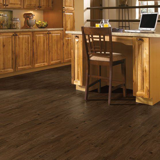 Dark wood kitchen floor with wooden cabinets and a barstool.